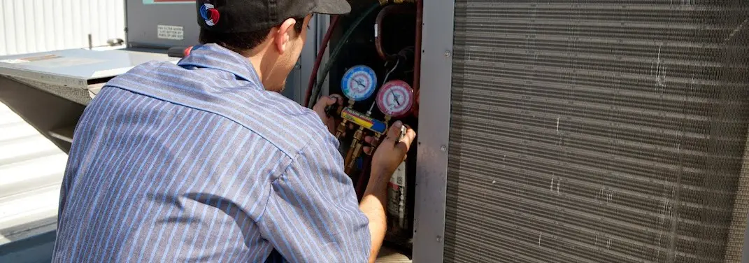 HVAC technician servicing a condenser unit in Woolwich